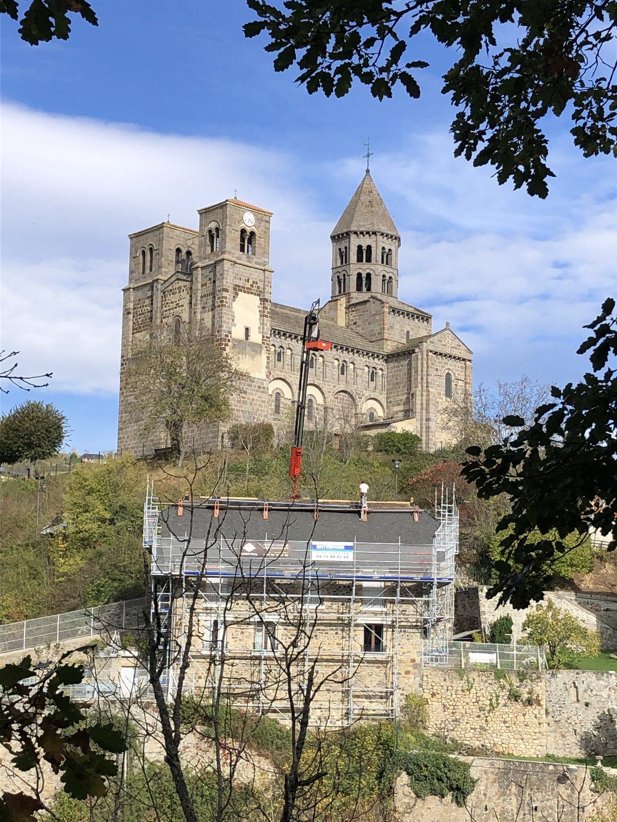 Chantier avec échafaudage et grue, église de Saint-Nectaire en fond