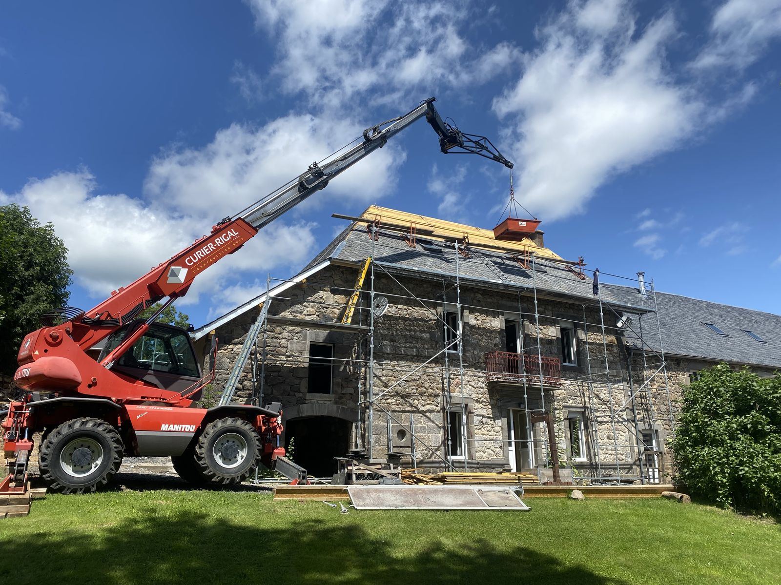 Chantier de rénovation : échafaudage et chariot télescopique devant une maison en pierre