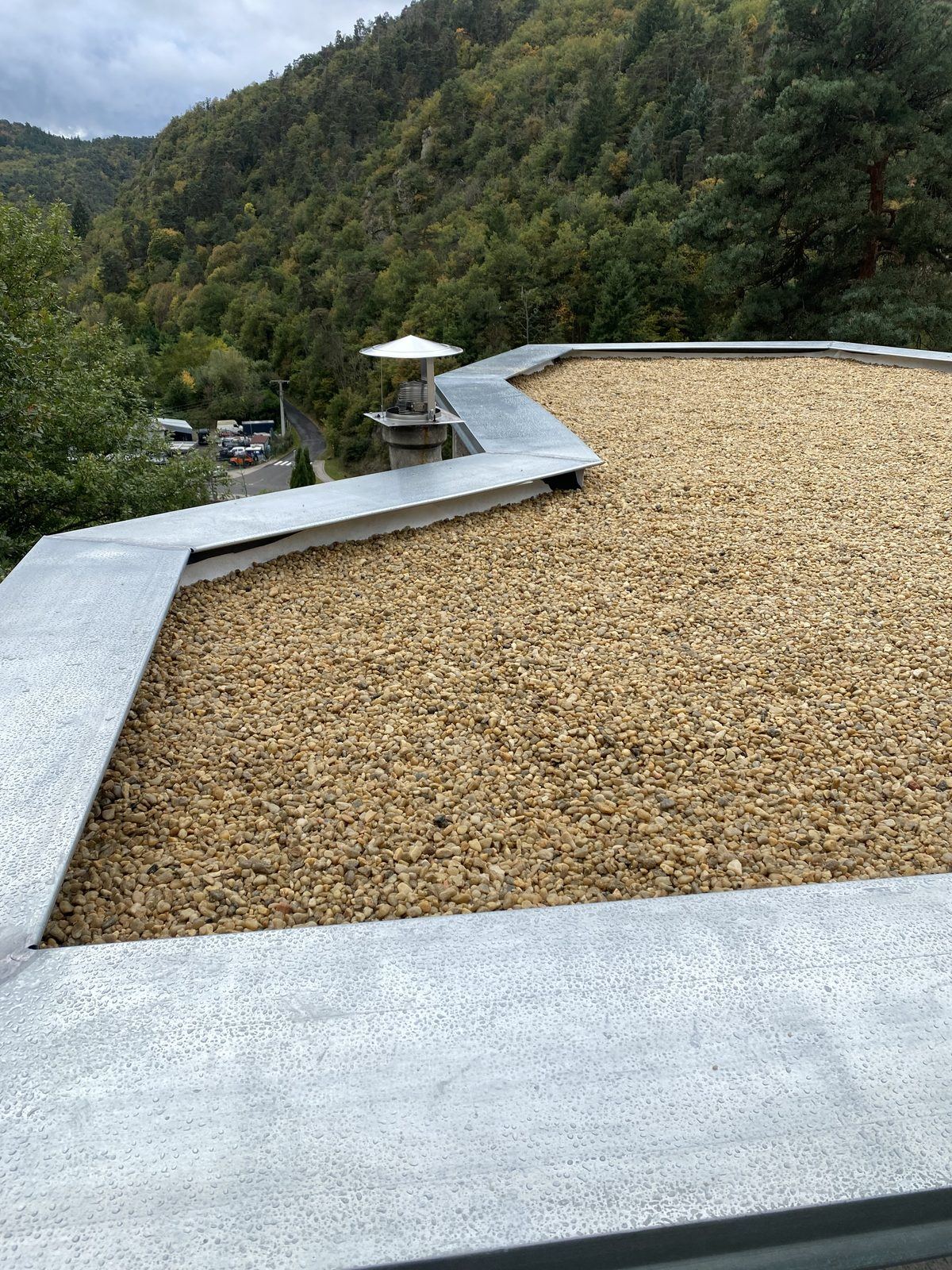 Toiture terrasse gravillonnée avec rive en zinc, colline boisée