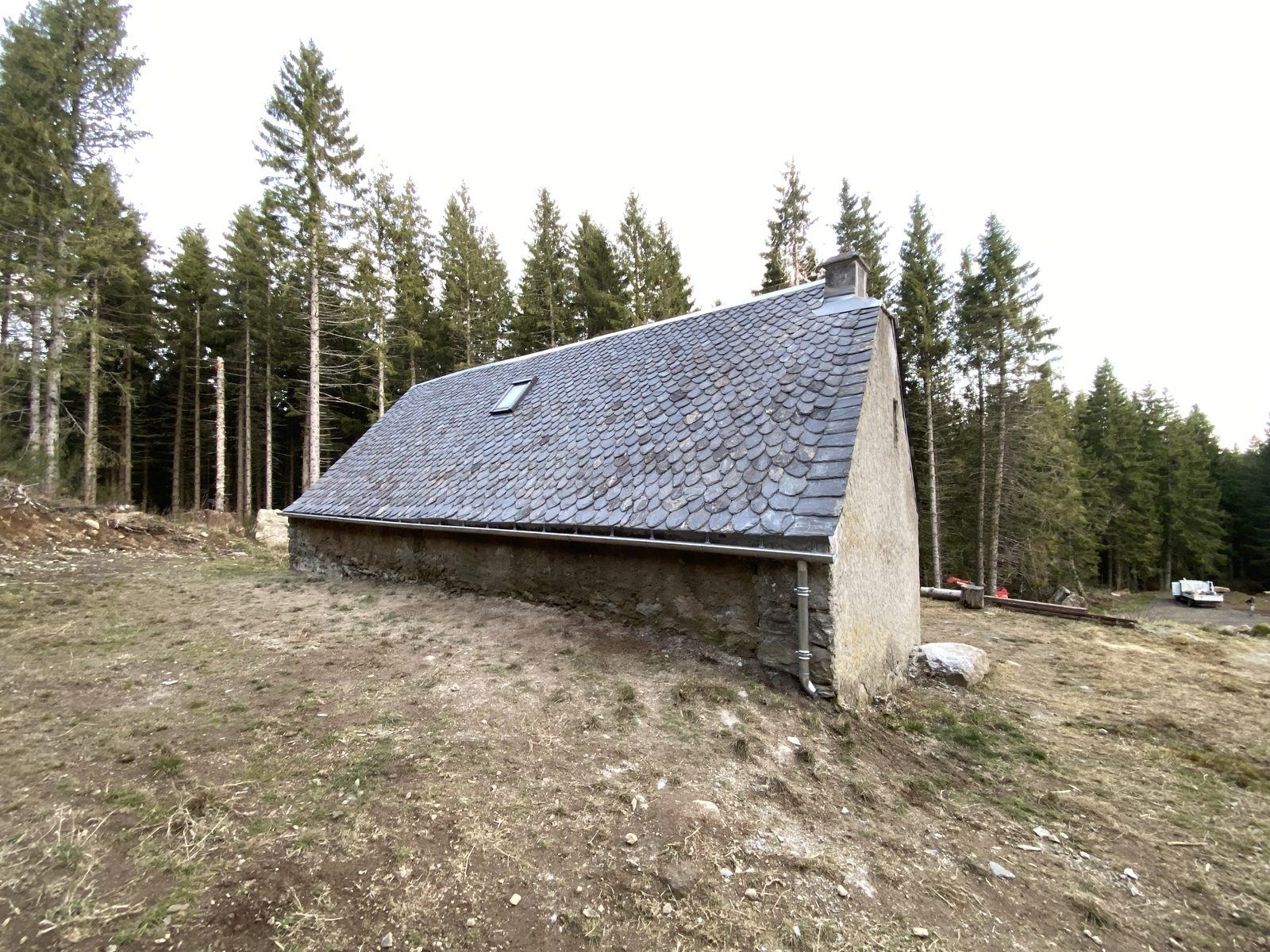 Couverture en ardoise écaille sur un bâtiment en pierre, forêt en arrière-plan