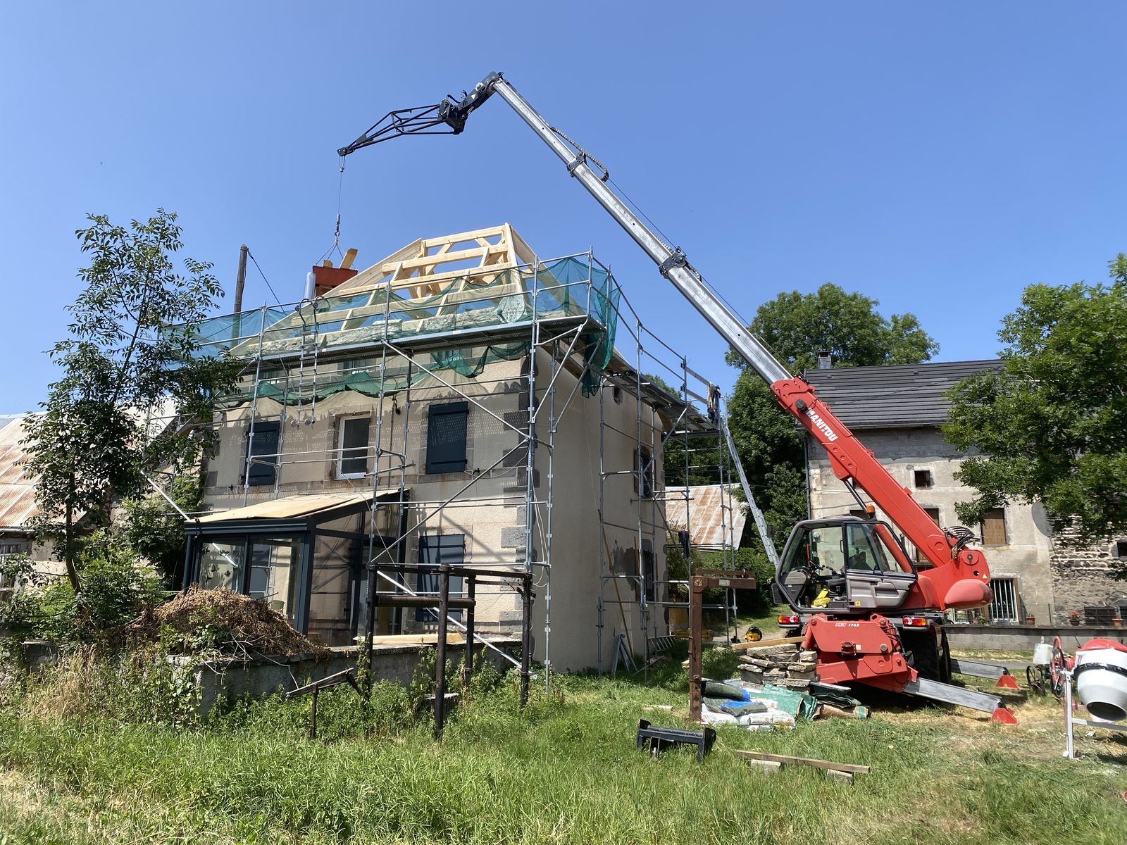 Bâtiment en pierre sous échafaudage, levage des matériaux par chariot télescopique